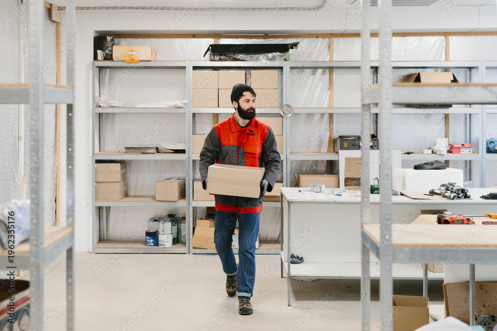 Fototapeta premium Worker carrying box in warehouse storage room