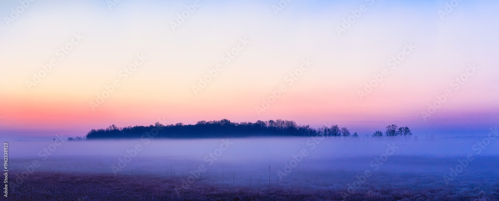 Fototapeta premium Panorama krajobraz rano z kolorowym niebem i mgłą na łąkach pod lasem