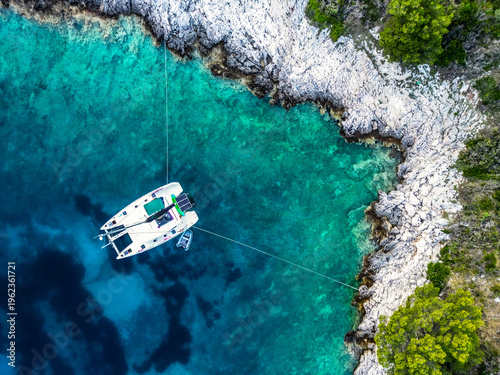 Foto Aerial top-down view of catamaran moored stern-to rocky limestone coastline with