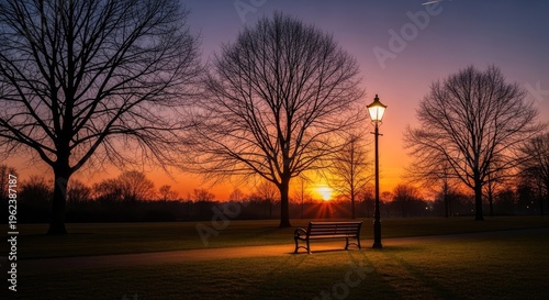 Evening park scene with bench and lamp post silhouetted against a sunset sky