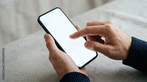Close up of male hands using smartphone with blank screen on sofa