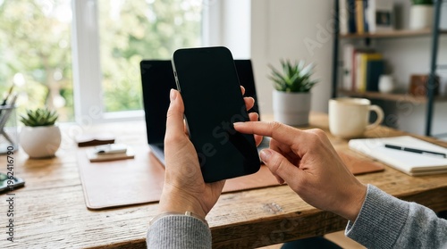 Hands using smartphone over desk with laptop and coffee mug