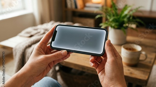 Hands holding smartphone horizontally with blank screen