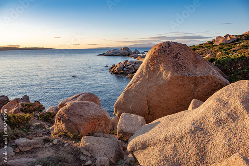 view on rocky coast at sunset in island of Sardinia in Italy with big rock under colorful sky