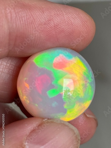 Hand holding a giant precious opal with super bright colors