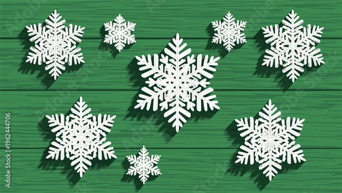 Several delicate white snowflakes of different sizes cast shadows on a dark green weathered wooden plank background.