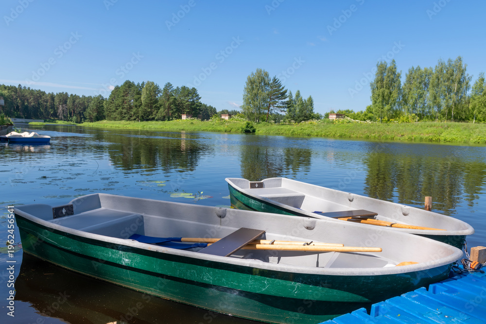 Obraz premium Plastic rowing boats at the river pier are ready for water trips, waiting for tourists.