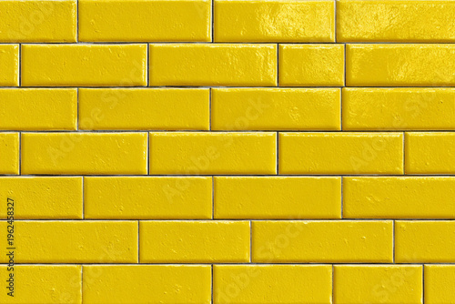 A vibrant wall of glossy yellow rectangular tiles arranged in a classic brick pattern