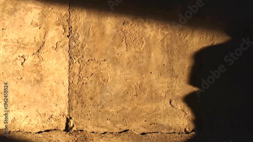 Shadow of a man in flat cap on textured wall