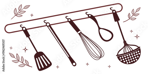 Assorted kitchen utensils hanging on a rustic metal bar with leafy accents