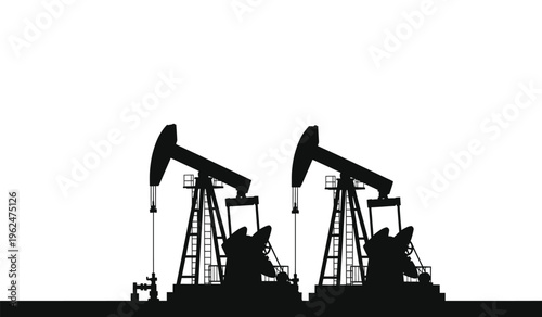 Silhouette of two oil pump jacks in industrial setting at night