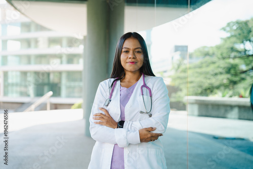 Foto Confident Latin female doctor or nurse with stethoscope standing with arms cross