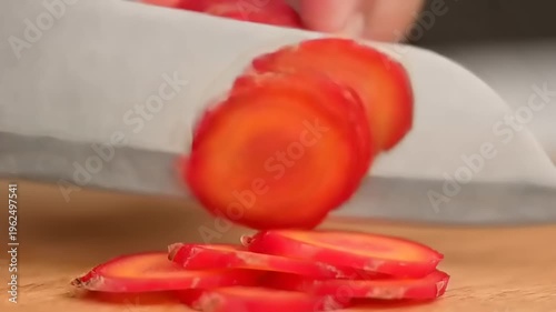 Slicing fresh red carrots with knife.