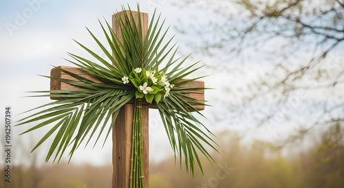Wooden cross decorated with palm leaves and white flowers symbolizing faith resurrection and Easter set against a soft blurred natural background