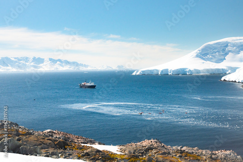 Expedition Cruise Ship and Kayakers in Antarctic Bay with Gentoo Penguin Colony - Scenic Polar Voyage in the Southern Ocean near the Antarctic Peninsula
