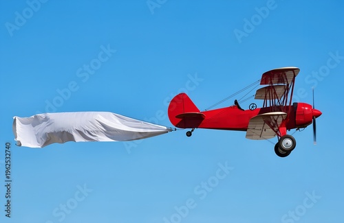 Aviation Banner in Sky: A vintage red biplane soars across a clear blue sky, towing a blank white banner, creating a dynamic visual, perfect for advertising and aerial marketing.