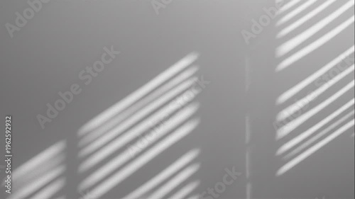 Shadows cast by window blinds create parallel lines on a plain wall, forming an abstract pattern in soft, diffused light