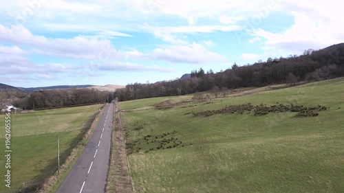 A low level ascent to reveal the main street of a picturesque rural village in Central Scotland nestled in a valley below the Campsie Hills. No road signs or location markers.

