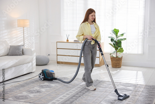 Photos Teenage girl cleaning carpet with vacuum cleaner at home