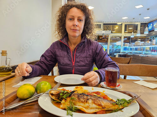 Wallpaper Mural Woman is sitting at a table with a plate of food in front of her. She is wearing a purple jacket and she is enjoying her meal Torontodigital.ca
