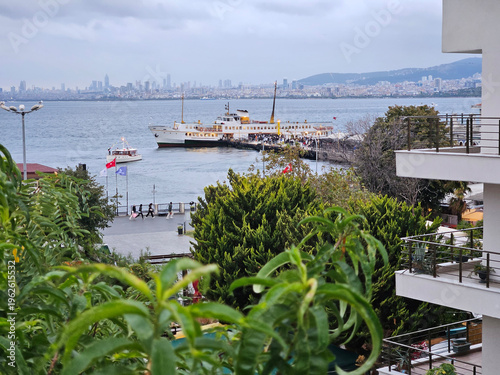 Wallpaper Mural Large ferry boat is docked at the pier in front of a city. The boat is a passenger ferry, and it is surrounded by a group of people who are likely waiting to board Torontodigital.ca