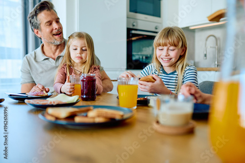 Foto Happy family bonding in modern kitchen, father and two daughters enjoying health