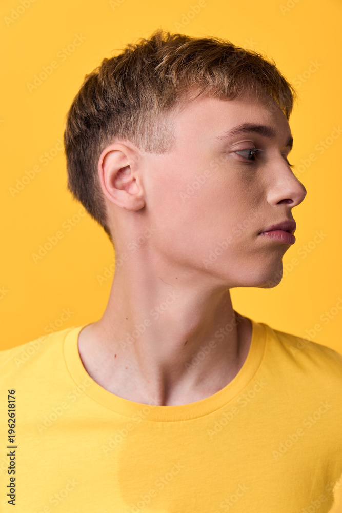 Naklejka premium Man profile in a yellow shirt, side view against a yellow background, showcasing clean lines, calm expression, modern fashion aesthetic, versatile stock image
