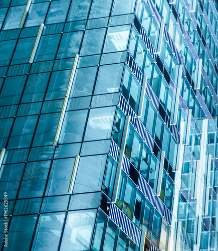 Abstract glass facade of modern office building with geometric pattern, reflections and blue tones in contemporary urban architecture