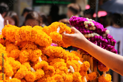 Fotografie A devotee placing a marigold garland as an offering at the Erawan Shrine in Bangkok, Thailand