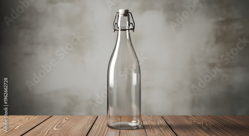Empty glass bottle with metal closure on a wooden table in front of a textured wall.
