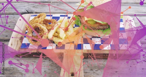 Camera pulling back revealing burger and sides on checked board, food overlays promoting menu