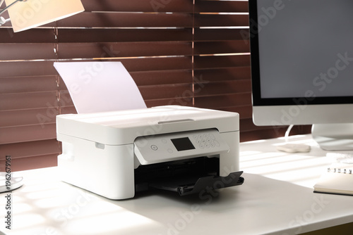 Modern printer and computer on white table in office, closeup
