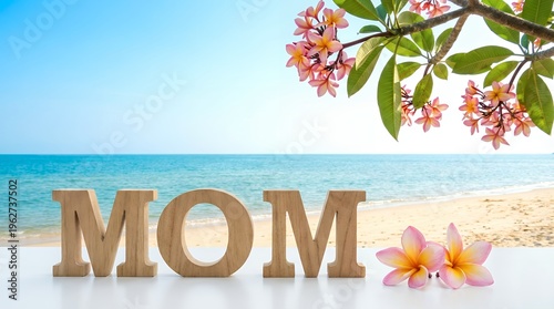 Wooden letters spelling MOM sit on a white surface against a beautiful tropical beach scene with blue ocean and pink flowers mother family love vacation holiday summer nature