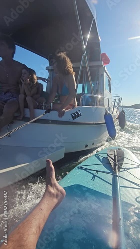 Man is holding a cell phone while riding a boat on a lake. The man is wearing a wristwatch and a watch band