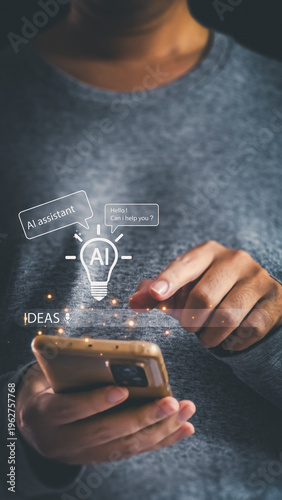 A man in a grey sweater holds a smartphone displaying a glowing holographic AI assistant lightbulb, chat bubbles, and an idea prompt bar for smart tech.