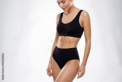 Fit young woman in black underwear showing toned abdomen in a bright professional fitness studio