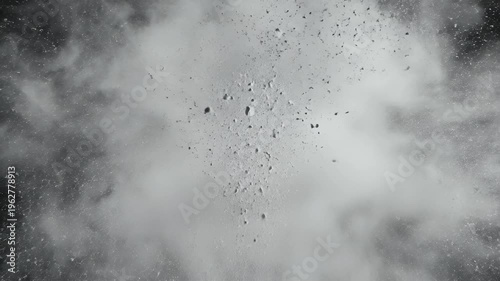 A cloud of white particles explodes outward against a stark black background