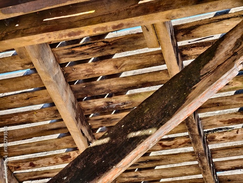 Low angle view of a rustic wooden bridge structure with weathered planks