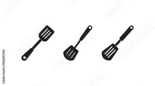 Three black kitchen spatulas with handles and holes for hanging on a white background  cooking utensils for flipping food