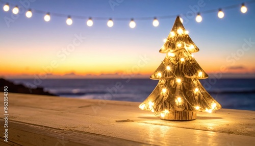 Lit ceramic tree sits on deck with ocean sunset. String lights above