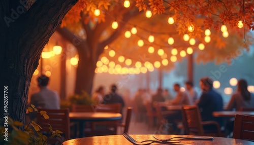 Outdoor cafe tables with warm string lights and autumn leaves overhead. People sit at tables in blurred background. Dusk creates cozy ambiance.