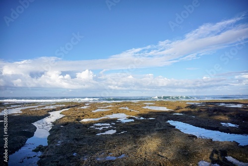 Wallpaper Mural Coastal view with rocky shore and ocean waves under a bright blue sky, showcasing natural seaside beauty. Torontodigital.ca