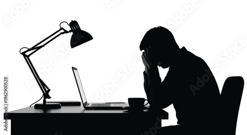 Silhouette of a stressed business professional overwhelmed by work sitting late at a desk with a laptop.