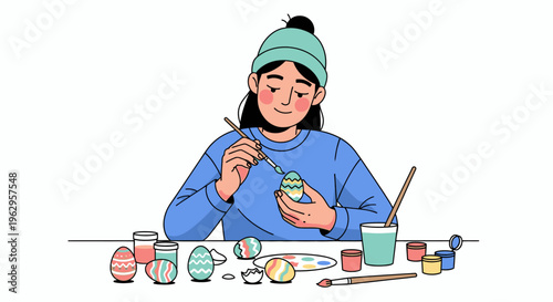A woman in a blue sweatshirt and green headband painting colorful Easter eggs with a brush at a table with paints and supplies.