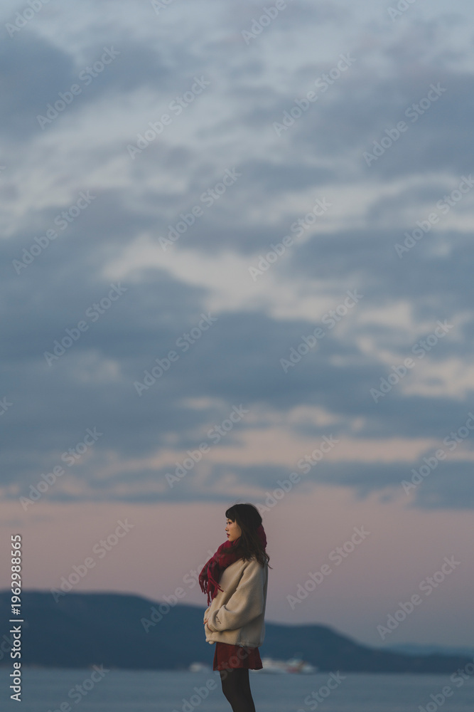 Obraz premium 夕暮れの海にいる女性