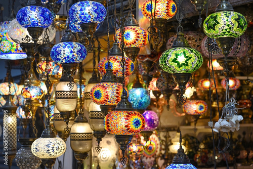 A colorful collection of intricately patterned mosaic glass lanterns hangs in a market