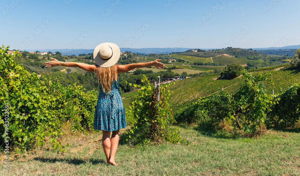 Naklejka premium Woman with open arms in a green vineyard in Tuscany, concept of freedom