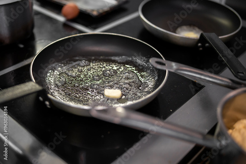 Tableau sur toile Butter melting and sizzling in a black non-stick frying pan on a modern inductio