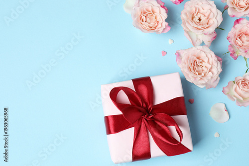 Beautiful pink roses, gift box on blue background. Mother's Day holiday concept
