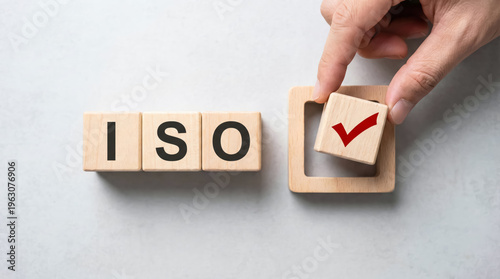 Hand placing a wooden block with a red check mark next to wooden blocks spelling iso
